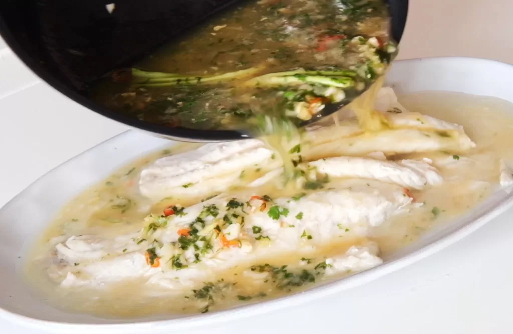 Pouring the broth on the steamed fish