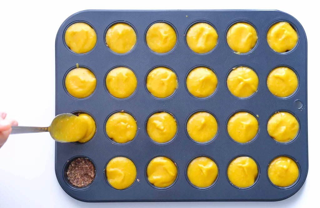 Scooping mango mix onto the tart base in the mold