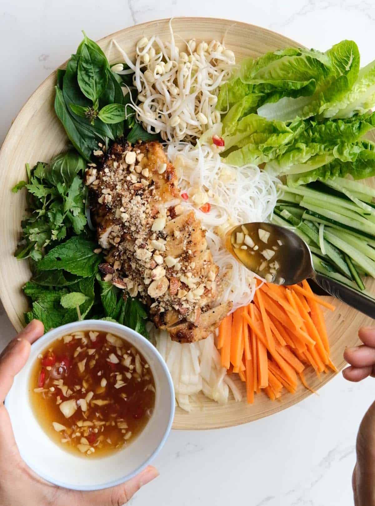 Pouring Vietnamese sauce onto Chicken Noodles Salad