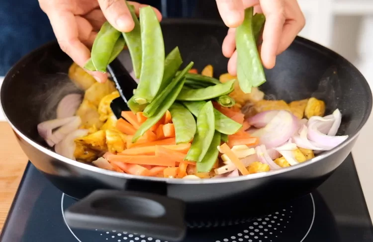 Step 3 on how to make turmeric and black pepper chicken: Add cut vegetables to the pan