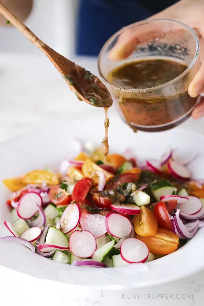 Drizzling Sumac sauce salad dressing on salad