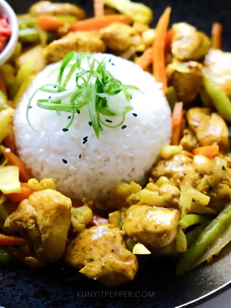 A close up of Turmeric Black Pepper Chicken Served with Rice topped with scallions