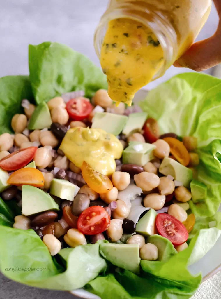 Pouring mango dressing on salad