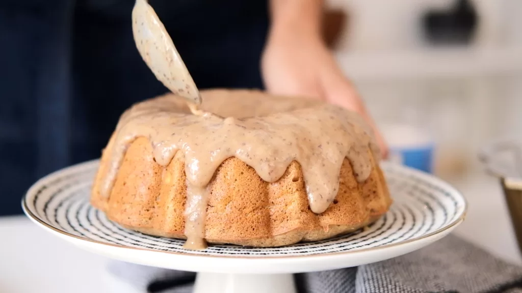 Glazing the bundt cake with the date caramel topping using a spoon