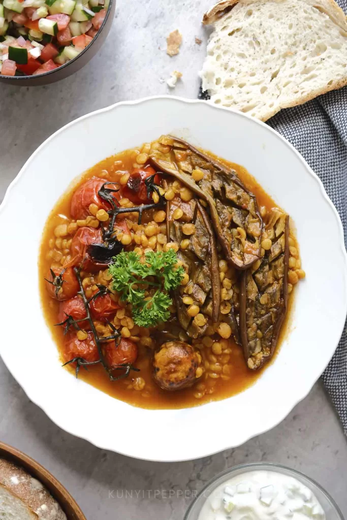 Yellow split peas stew with eggplants and tomatoes alongside other side dishes