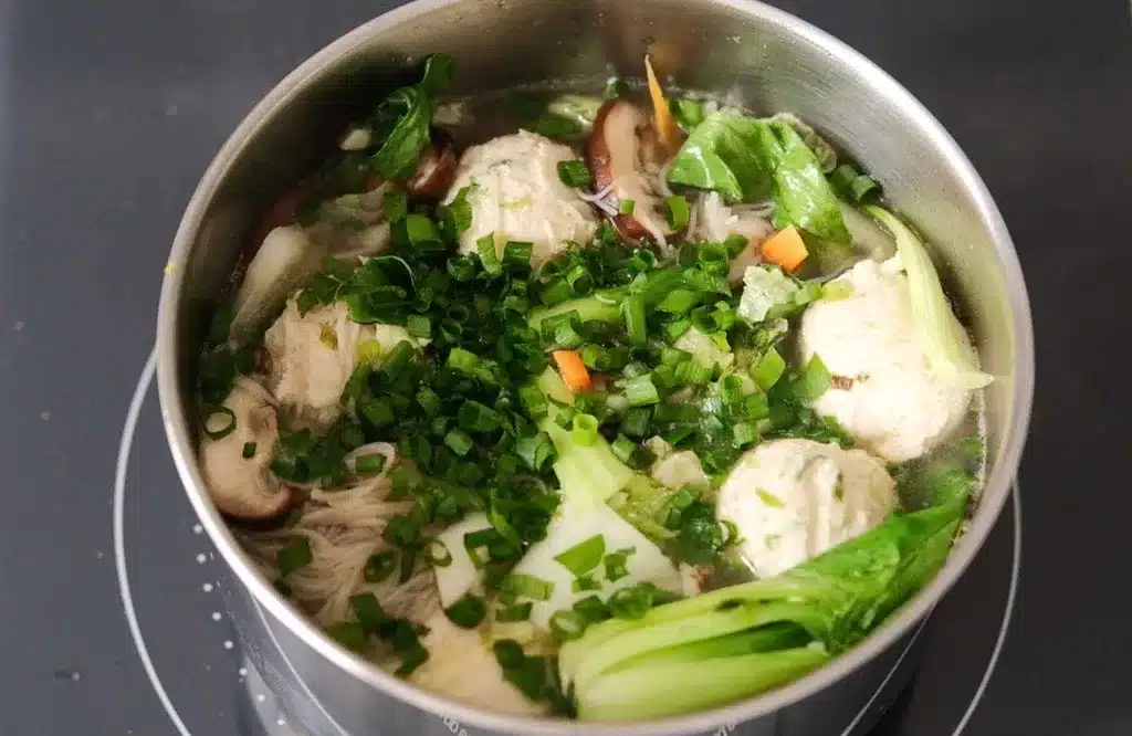 Asian chicken meatball noodle soup garnished with green onion