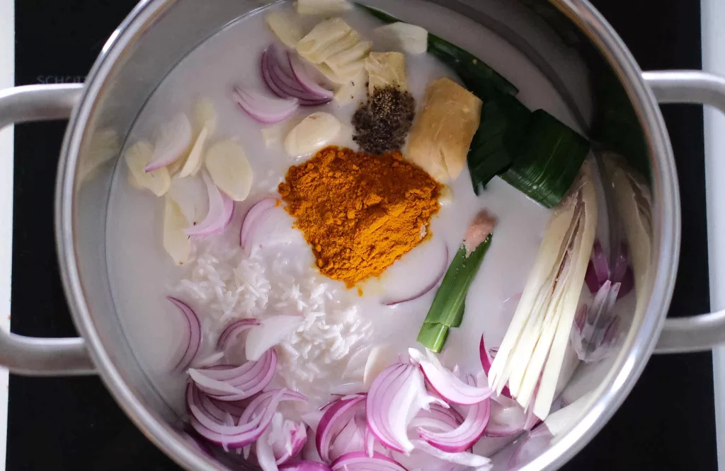 Mixing turmeric rice ingredients in a pot on a stovetop