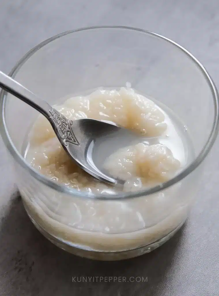 Scooping fermented rice in a glass jar