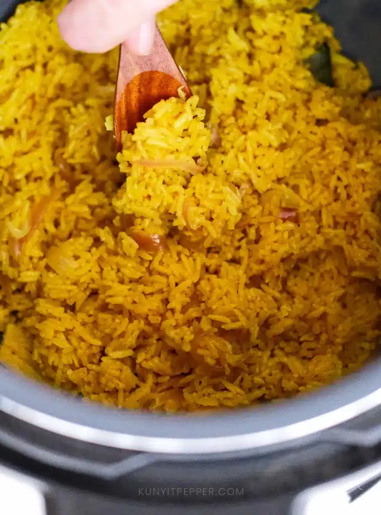 Scooping turmeric rice in instant pot with wooden spoon