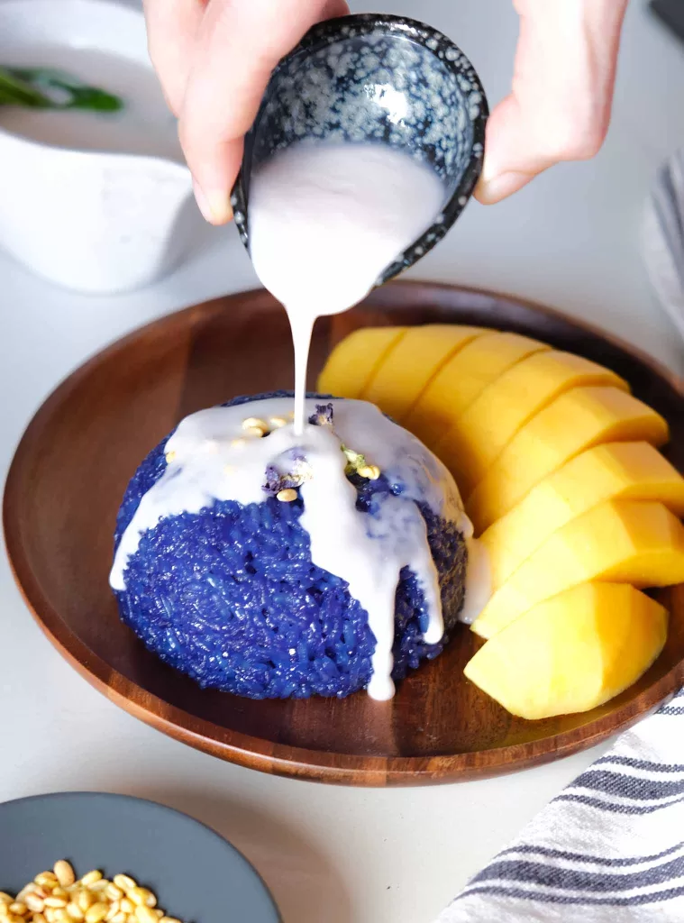 Drizzling coconut milk on Thai Blue Mango Sticky Rice