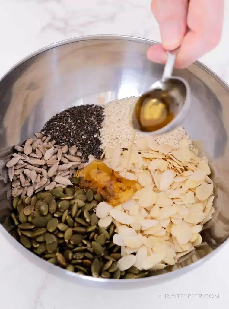 Pouring honey in a bowl with almond and seeds