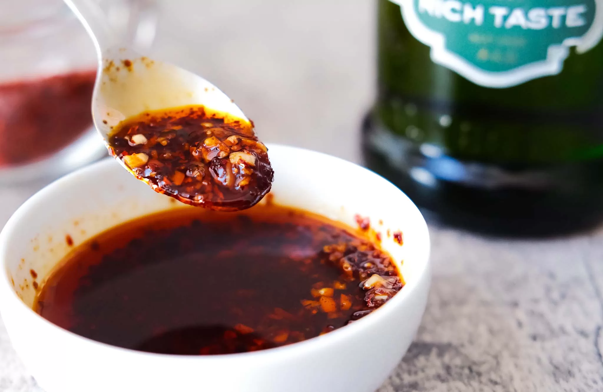 Spooning Chili Oil with Olive Oil in a white bowl