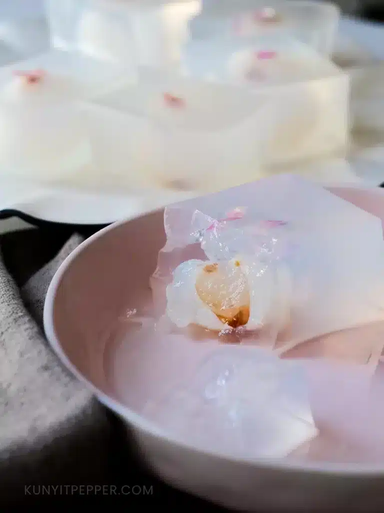 Piece of Coconut Jelly with Lychee in a dish with stacked of cubes behind