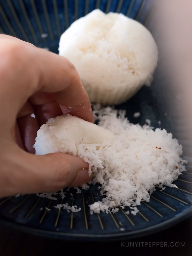Pinching steamed sweet rice cake with grated coconut